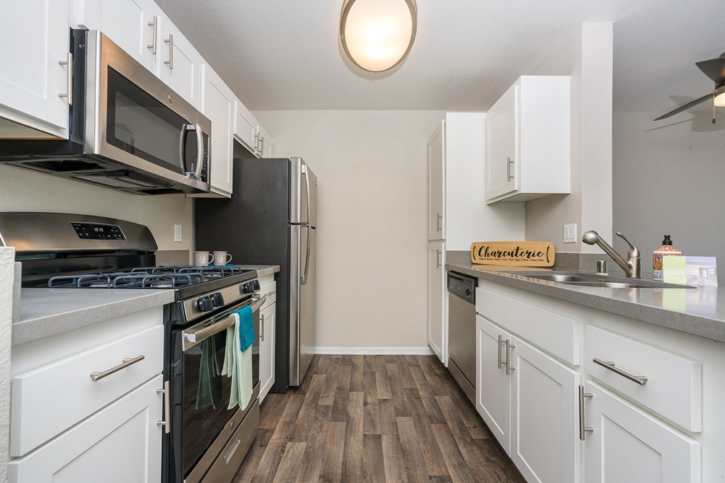 a kitchen with white cabinets and stainless steel appliances at 55+ FountainGlen Temecula, Temecula