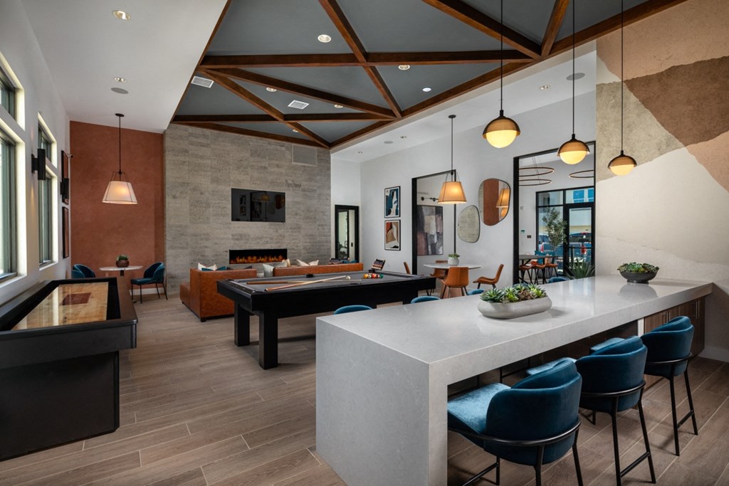 a clubhouse with a pool table and a bar with blue chairs