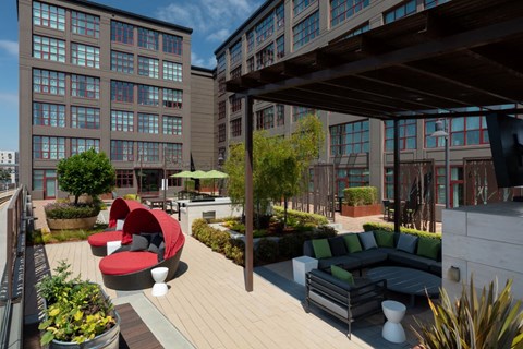 a rendering of a rooftop patio with couches and chairs at Aqua Via Apartments, Oakland, CA