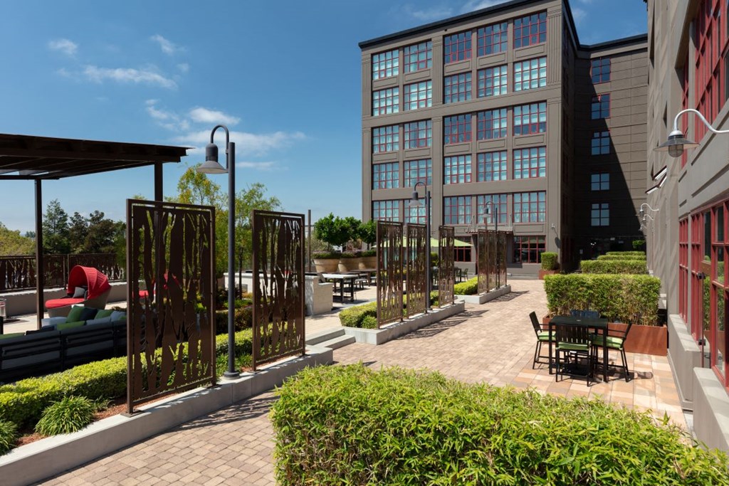 a courtyard with tables and chairs and a building in the background