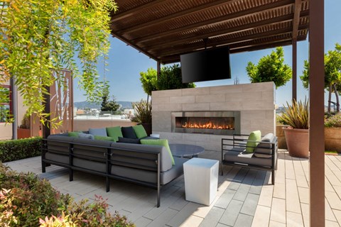 Oakland Apartments for Rent - Aqua Via - Community Patio with a Fireplace, a TV, and Lounge Chairs at Aqua Via Apartment, California