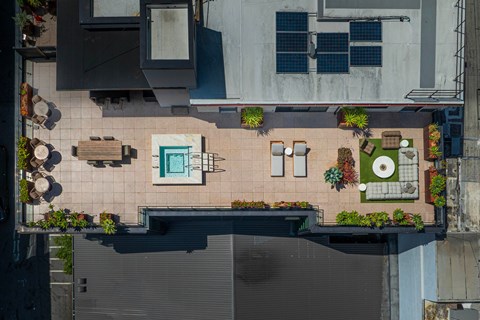 A rooftop patio with a table and chairs and a pool.
