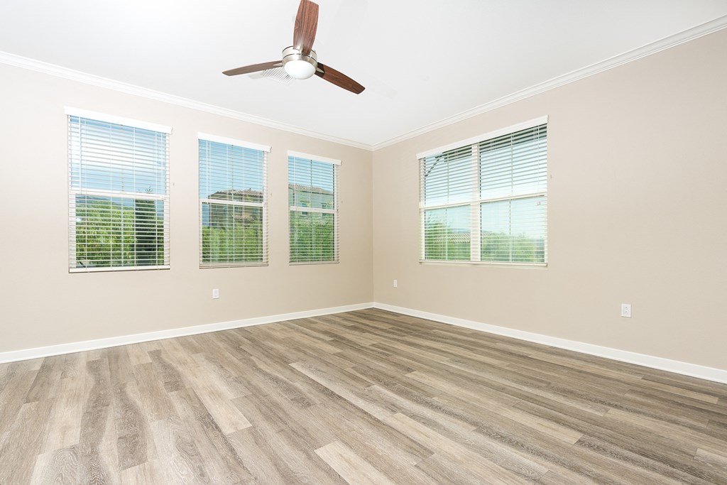 bedroom with windows and ceiling fam and wood style flooring.