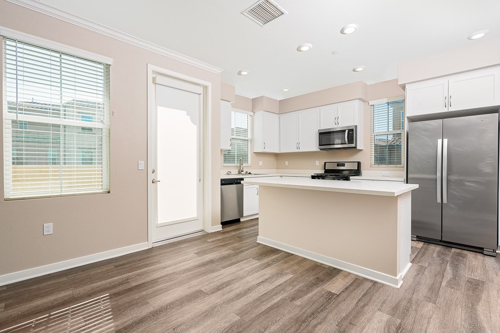 a kitchen with white cabinets, stainless steel appliances and kitchen island