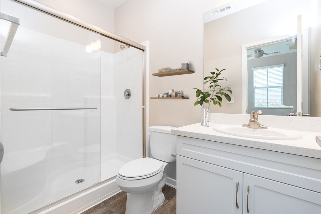 a bathroom with a white sink and toilet next to a shower with a glass door