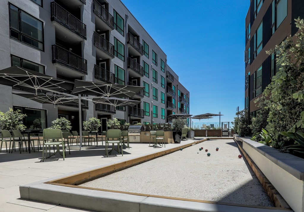 Apartments in Brooklyn Basin Oakland, CA for Rent - Artizan - BBQ Area with Tables, Chairs, Umbrellas, Grilling Station, and a Bocce Playing Court
