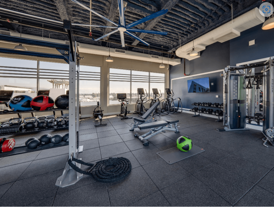 a gym with weights and other exercise equipment and a large window
