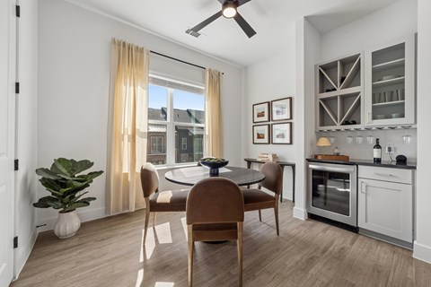 A modern dining room with a table set for two and a potted plant on the side table.