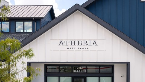 A white building with a black roof and a sign that says Atheria West Grove.