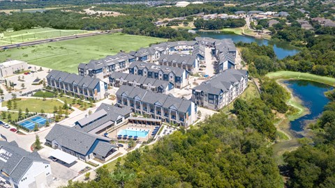 A bird's eye view of a resort with a large building and a pool.