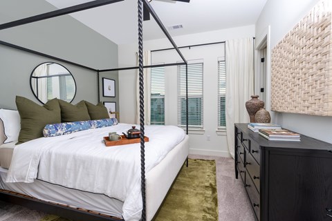 A bedroom with a four poster bed and a dresser.