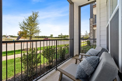 A balcony with a bench and pillows overlooking a street.