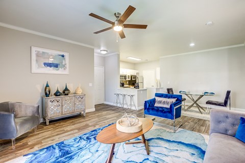 A living room with a blue rug and a ceiling fan.