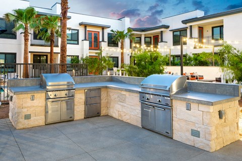 A modern outdoor kitchen with a stone counter and stainless steel appliances.
