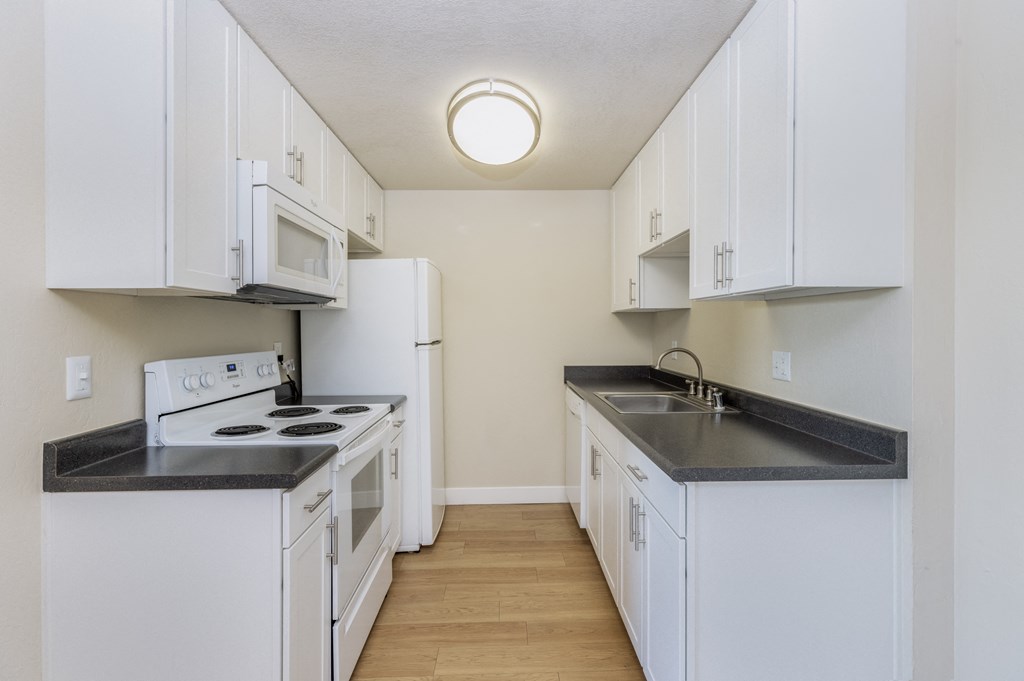 One-Bedroom Apartments in Redwood City, CA - Avenue Two - Kitchen with Granite Countertops, White Cabinets, White Appliances, and Hard Surface Flooring at Avenue Two Apartments, Redwood City  , CA