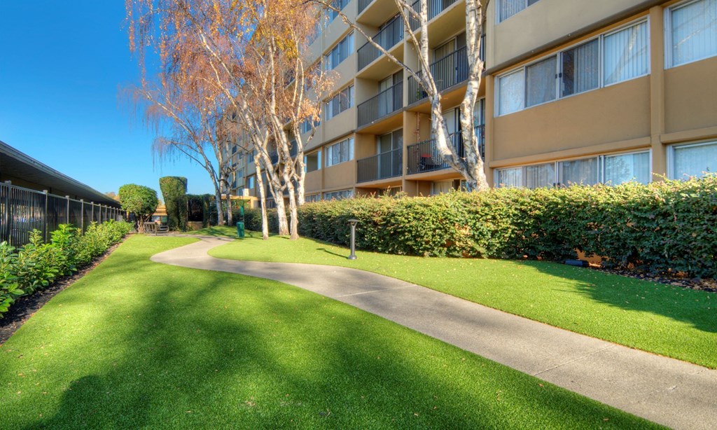 Apartments in Redwood City for Rent - Avenue Two - Dog Park with Green Grass, a Sidewalk, a fence, and Bushes at Avenue Two Apartments, California, 94063