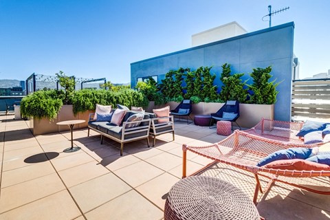 a rooftop terrace with furniture and plants on a sunny day