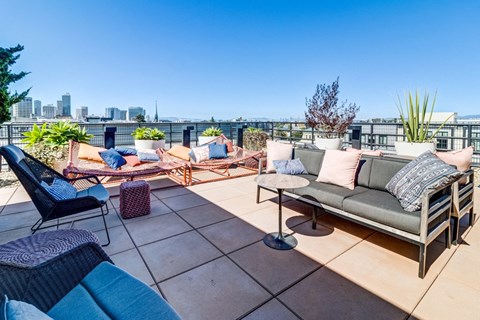 a rooftop patio with couches and chairs and a city in the background