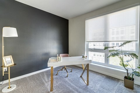 an office with a large window and a white desk with a chair and a plant