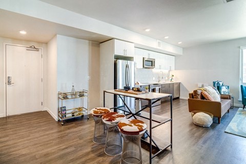 a living room with a kitchen and a table with four stools