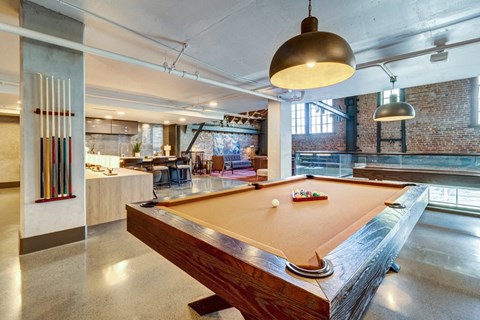 a pool table in a living room with a bar and other amenities