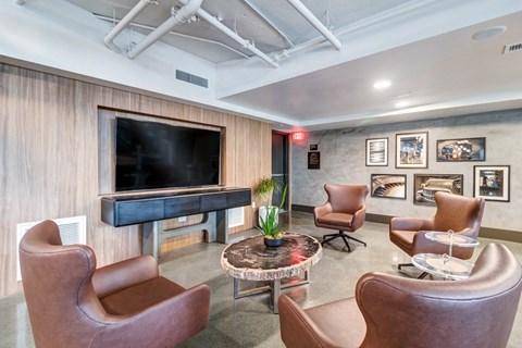 a living room with leather chairs and a television