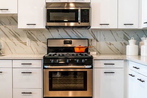 A modern kitchen with a stove top oven and microwave above it.