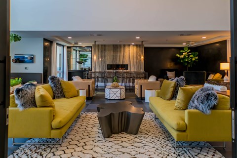 A living room with yellow couches and a patterned rug.