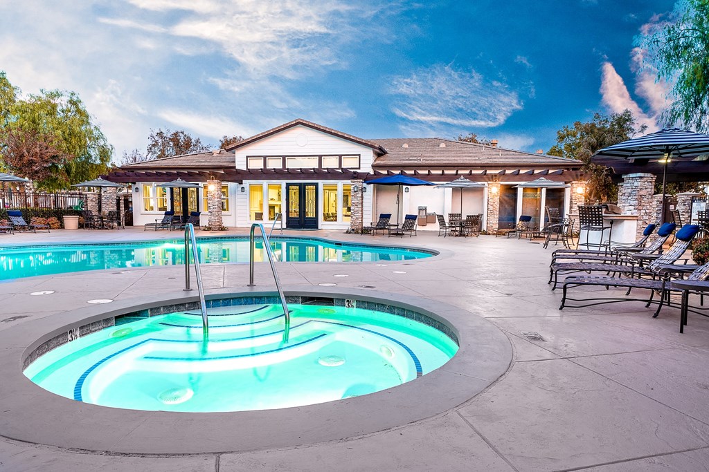 Three Bedroom apartments in Rancho Cucamonga CA - Barrington Place - Pool with Lounge Chairs, Tables with Chairs, Umbrellas, Spa, and View of Clubhouse in the Background