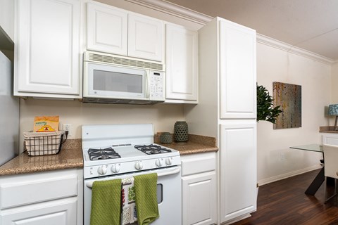 a kitchen with white cabinets and a white stove and microwave