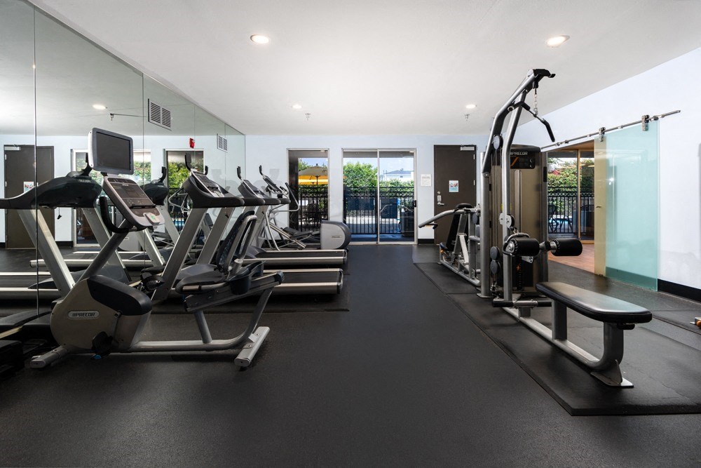 a gym with treadmills and other exercise equipment on a black floor