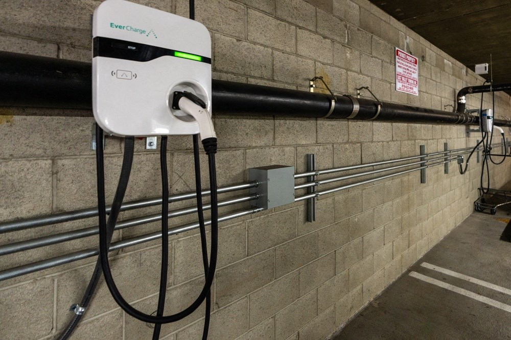 a white electricity meter on a brick wall with wires plugged into it