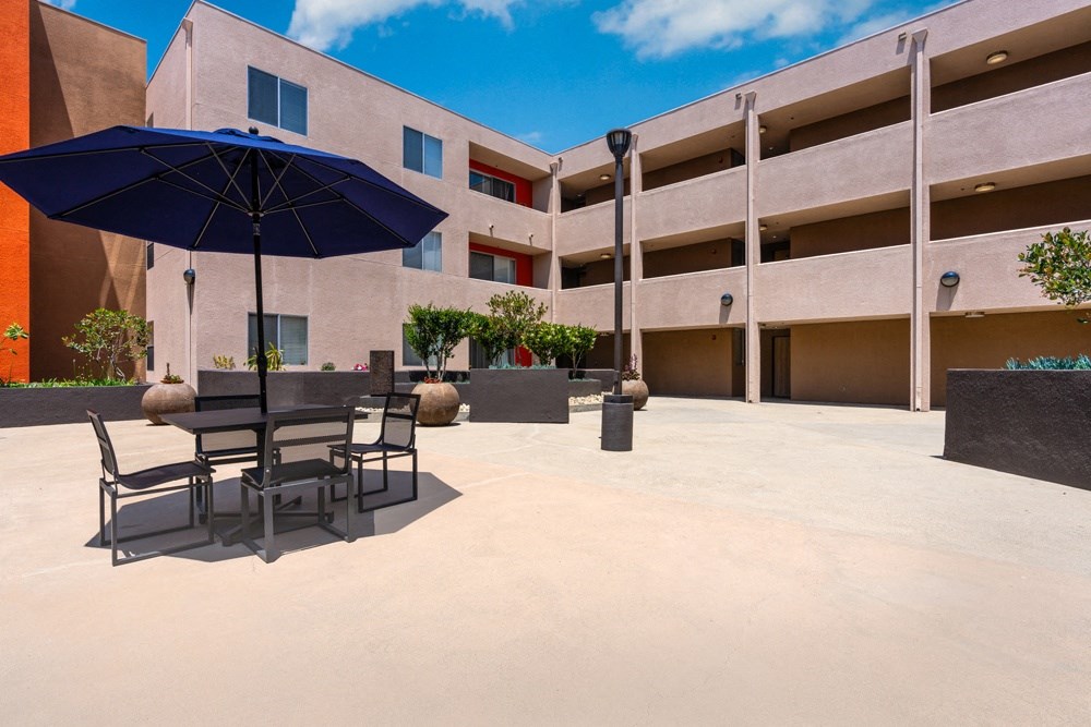 a patio with tables and umbrellas in front of a building