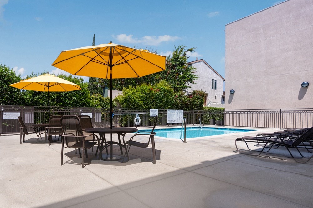 our apartments have a pool and a patio with chairs and umbrellas
