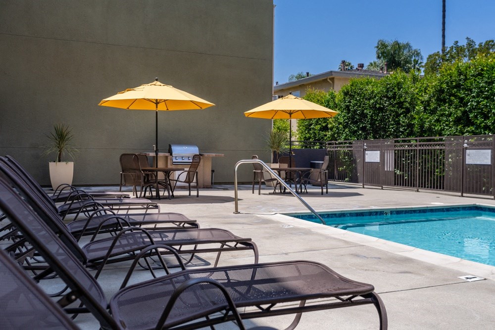 a swimming pool with chairs and umbrellas next to it