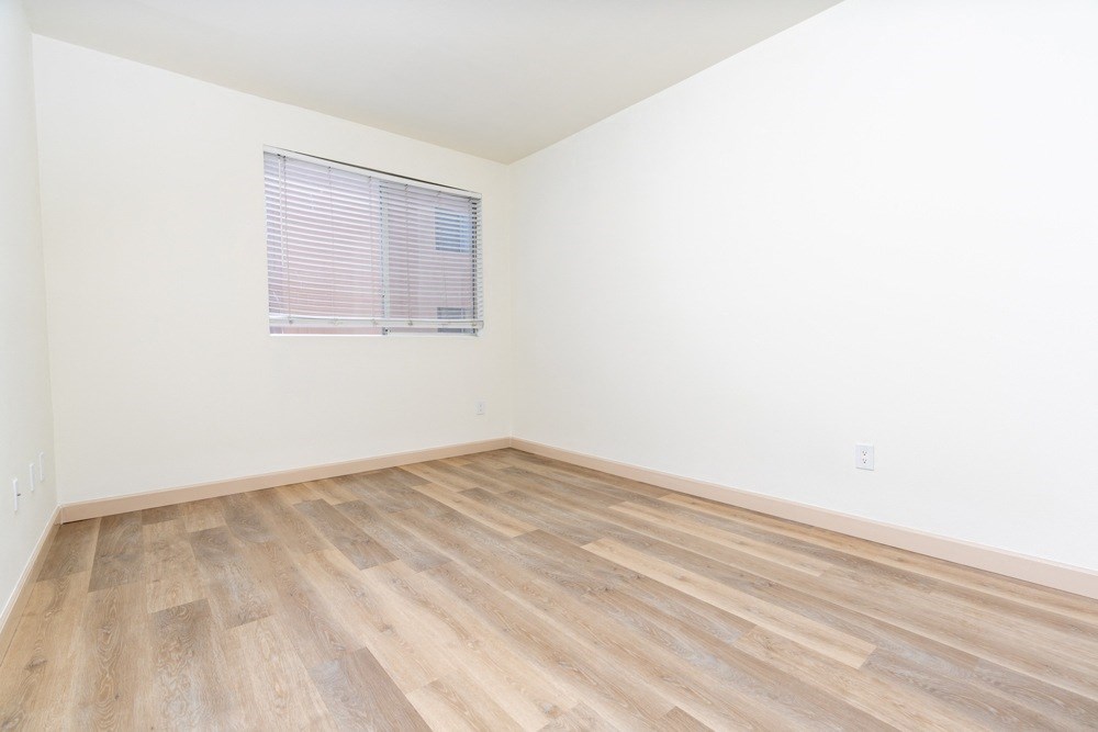 an empty room with wood floors and a window