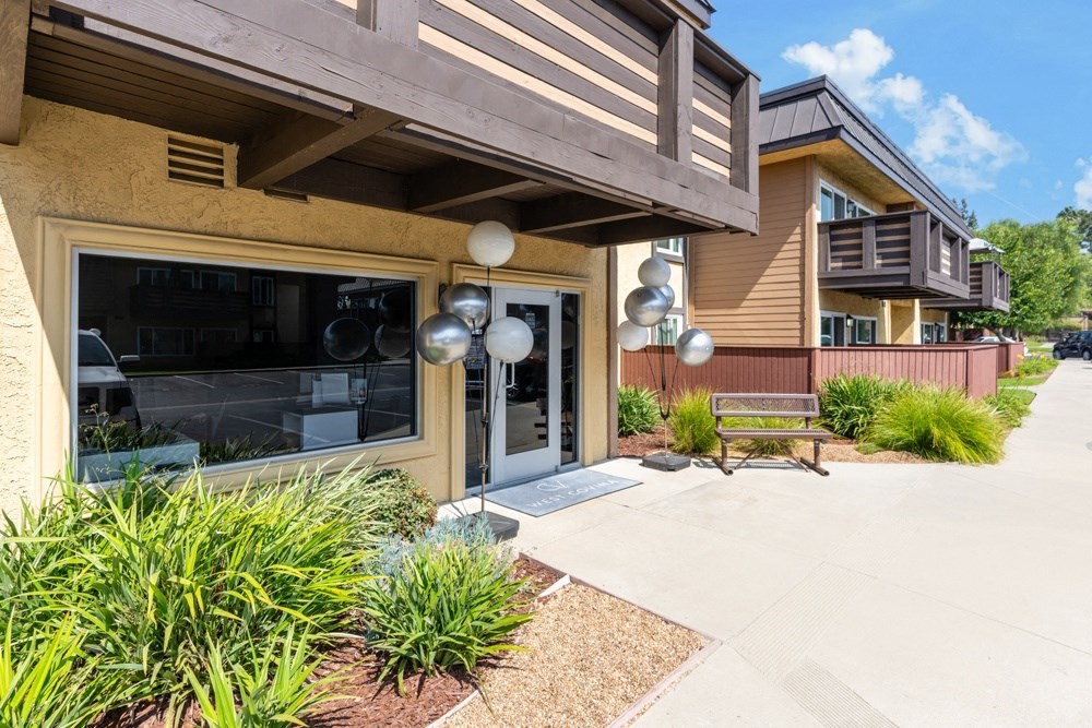 a patio in front of a building with a bench and plants
