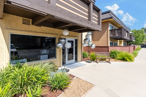 a patio in front of a building with a bench and plants