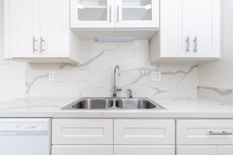 a white kitchen with a sink and white cabinets