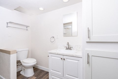 A white bathroom with a toilet, sink, and medicine cabinet.