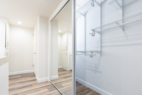 a walk in closet with a mirrored closet door in a white room