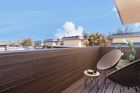 A balcony with a chair and a table with food on it.