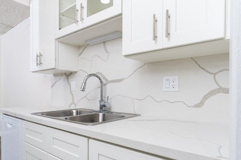 a white kitchen with a sink and white cabinets