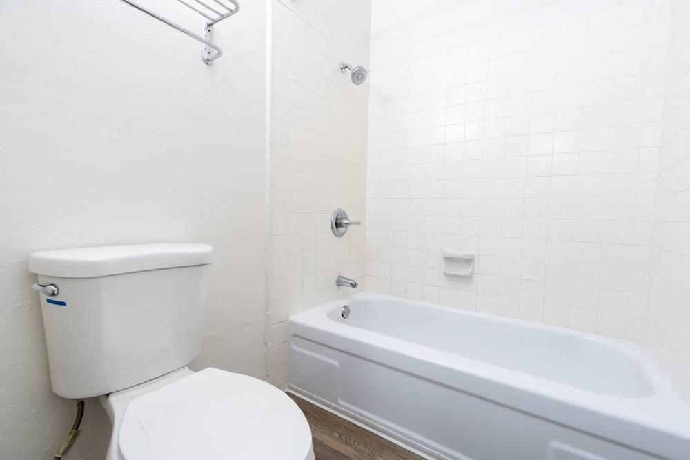 a white bathroom with a toilet and a tub