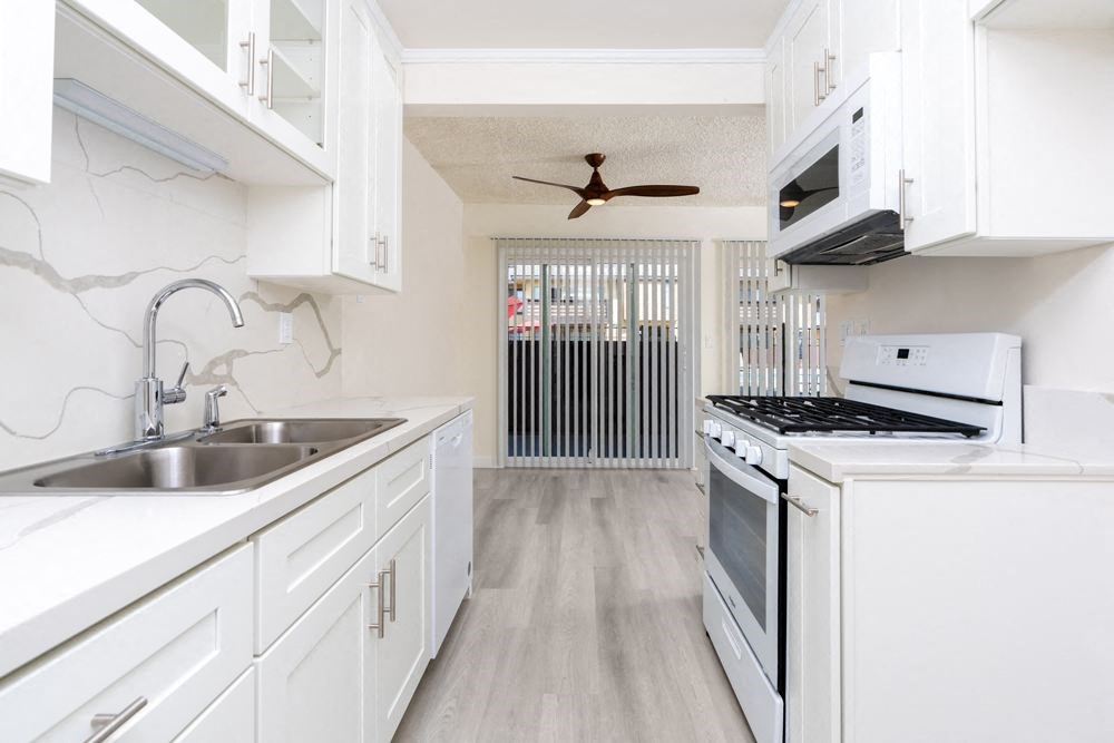 A white kitchen with a fan and a stove.