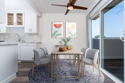 a dining area with a table and chairs and a ceiling fan