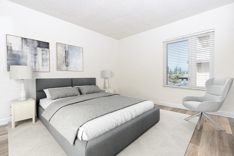 a bedroom with a bed and a chair and a window