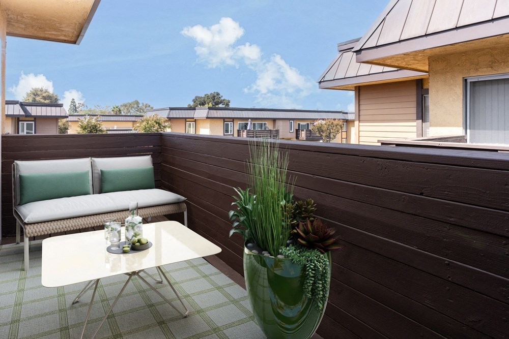a balcony with a couch and a table and a potted plant