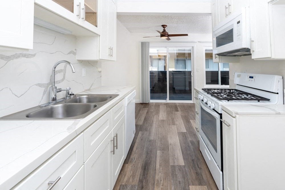 a kitchen with white cabinets and a stove and a sink