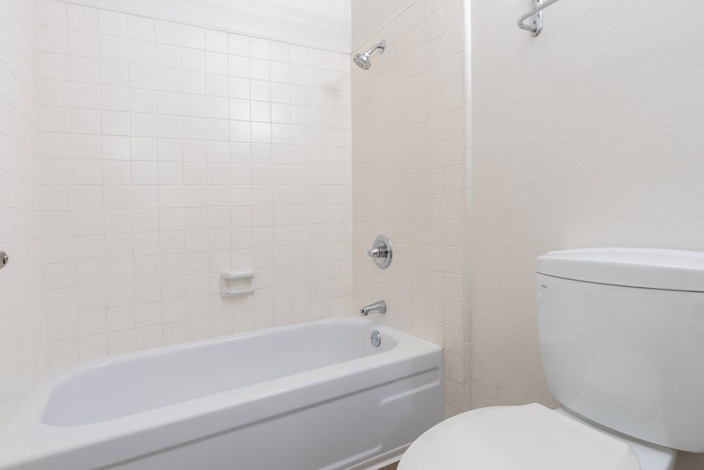 A white bathroom with a tub and toilet.